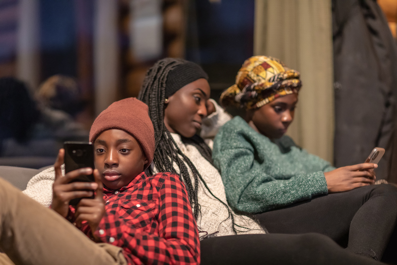 Young people sitting together looking at their phones Young people sitting together looking at their phones