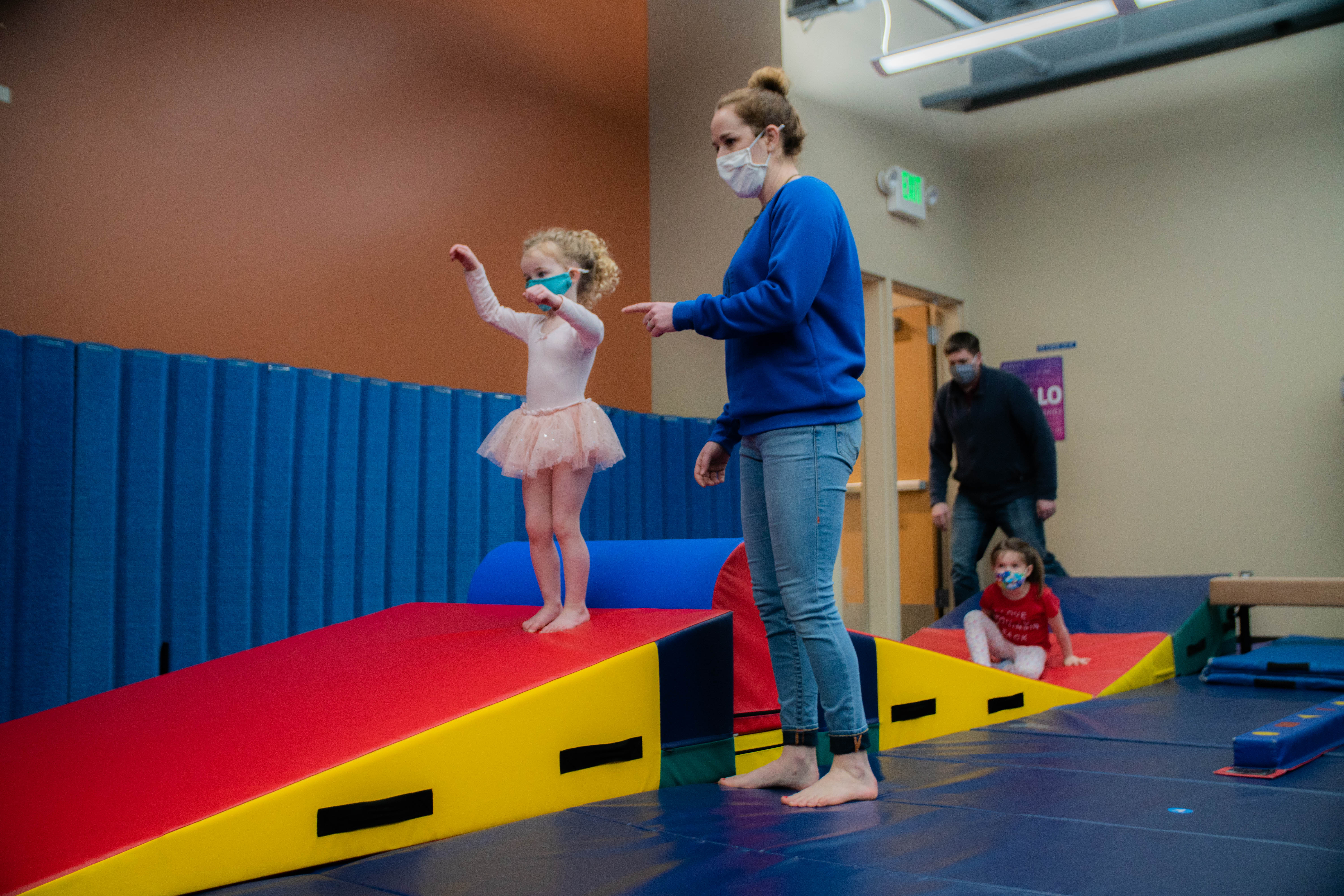 YMCA staff member working with young child in dance and gymnastics class YMCA staff member working with young child in dance and gymnastics class