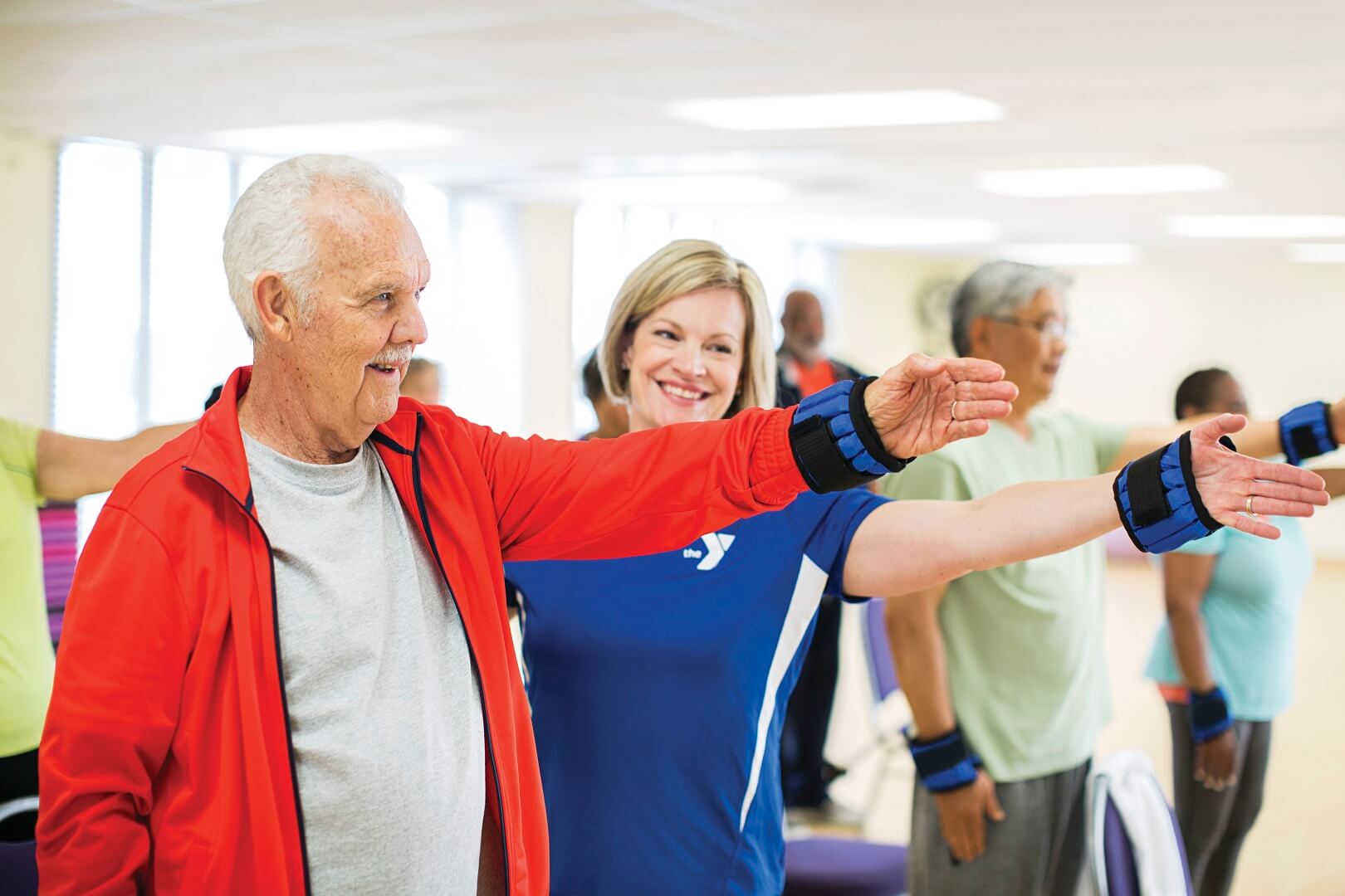 Older man and instructor lifting weighted arm band at YMCA Louisville Older man and instructor lifting weighted arm band at YMCA Louisville