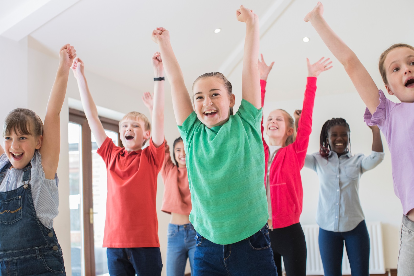 Kids raising hands in the air, celebrating and dancing together Kids raising hands in the air, celebrating and dancing together