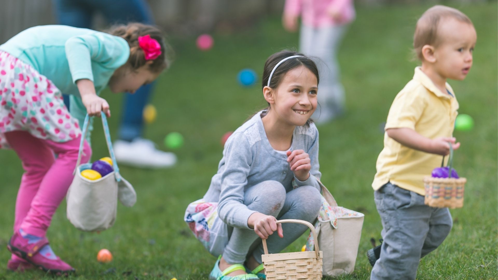 3 smiling young children hunting Easter eggs outdoors 3 smiling young children hunting Easter eggs outdoors