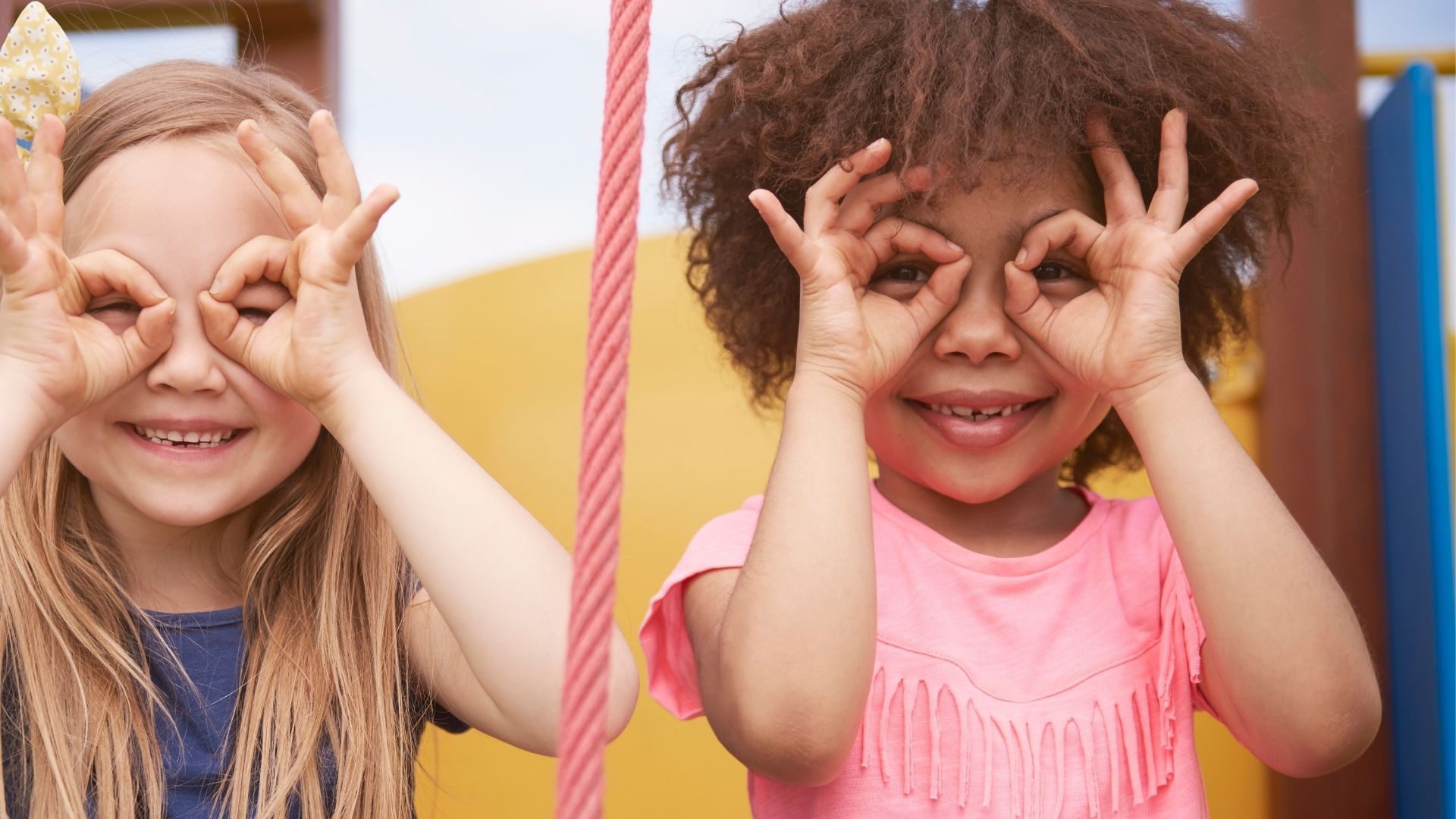 Two smiling young girls acting like they are wearing glasses by using their hands Two smiling young girls acting like they are wearing glasses by using their hands