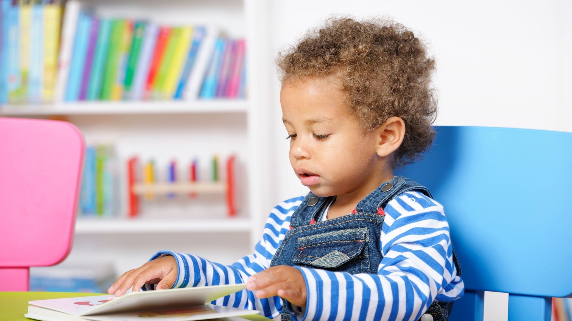 Toddler sitting in chair reading a book Toddler sitting in chair reading a book