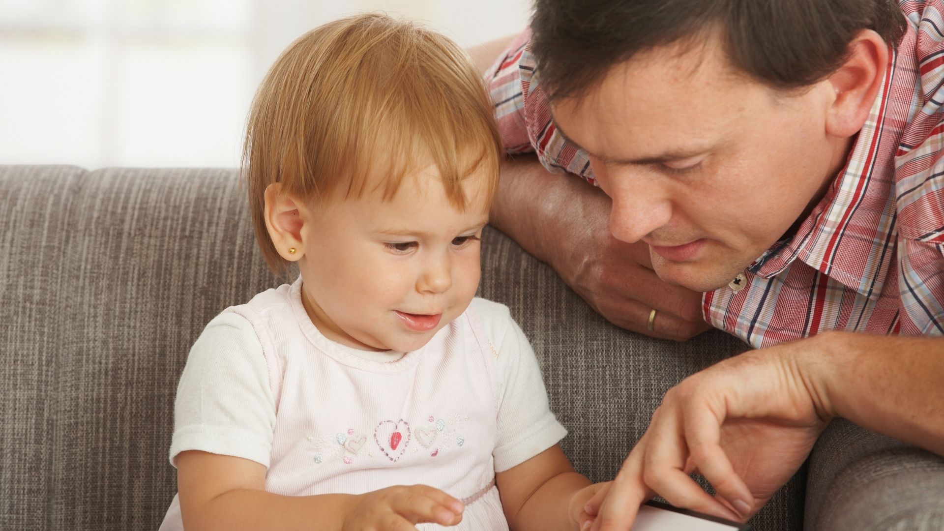 Toddler holding a book with a man pointing at a picture in the book Toddler holding a book with a man pointing at a picture in the book