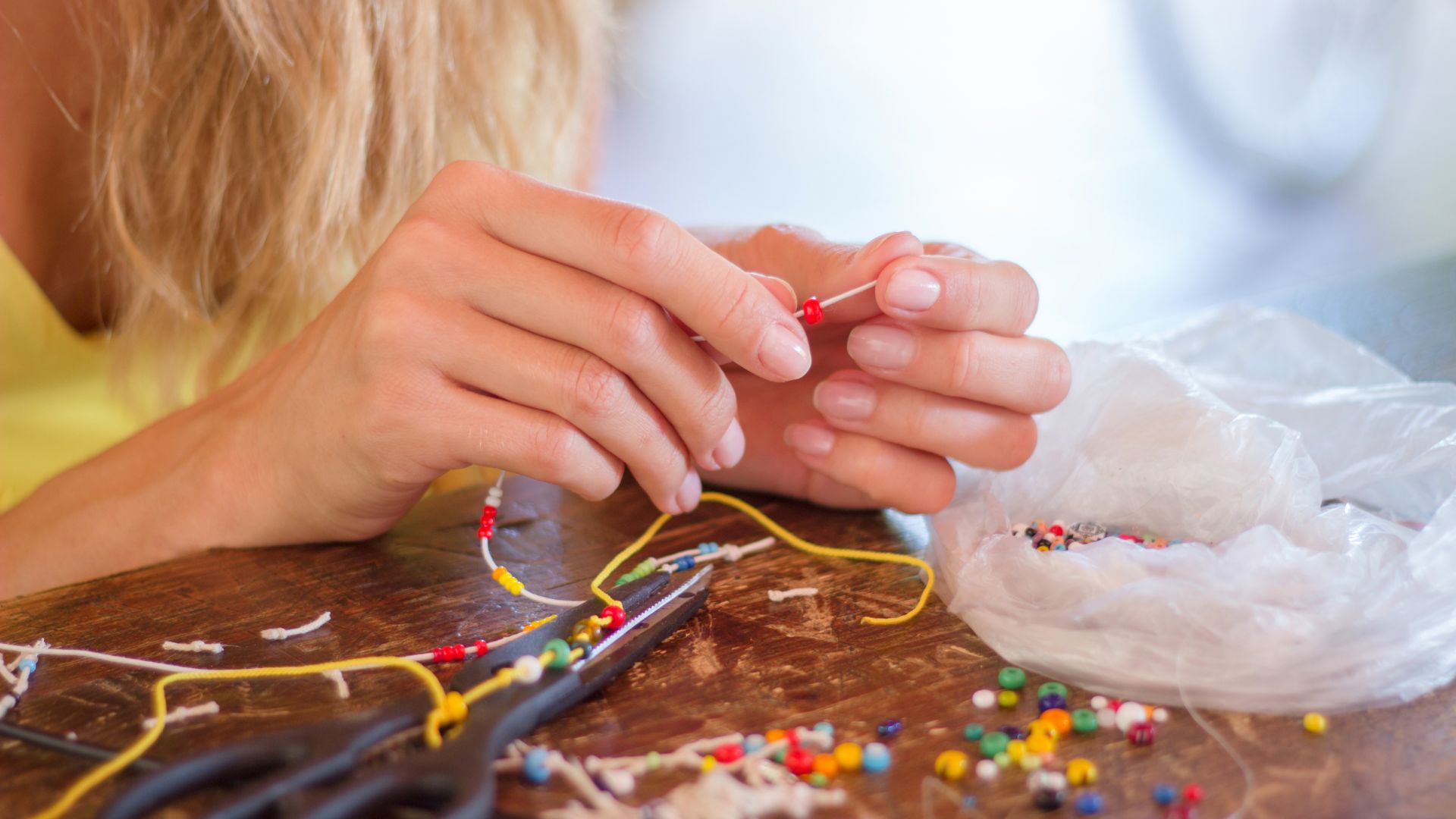 Person at table crafting a necklace Person at table crafting a necklace