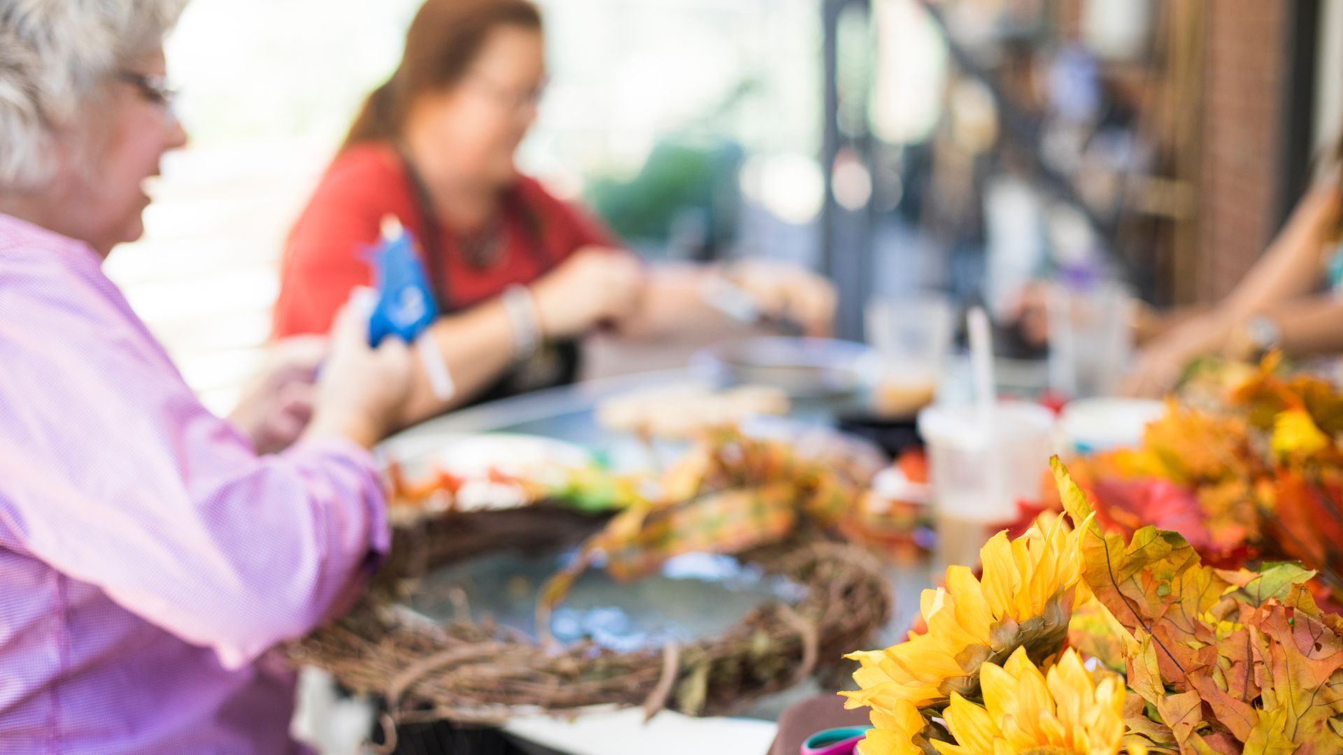 Adults crafting fall-themed wreaths together Adults crafting fall-themed wreaths together