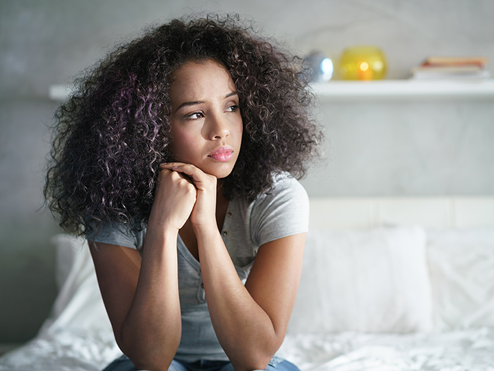 Girl sitting in bed looking sad Girl sitting in bed looking sad