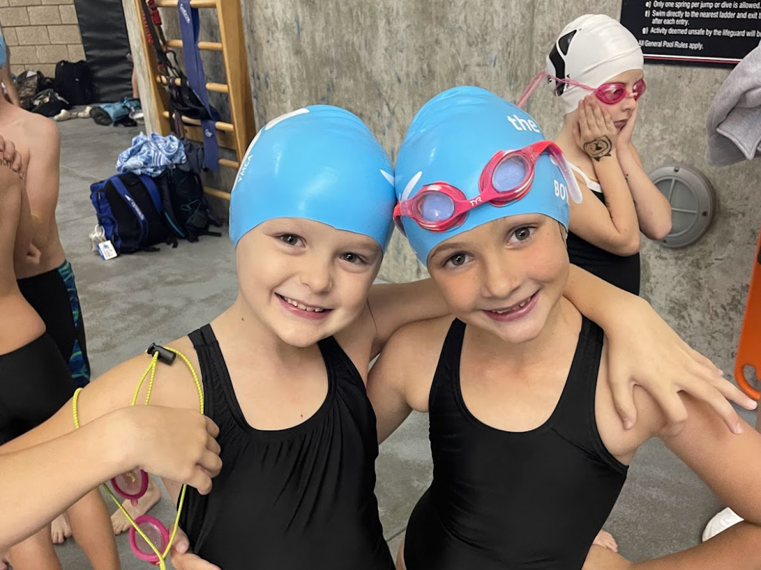 Two girls wearing black swimsuits and blue swim caps Two girls wearing black swimsuits and blue swim caps