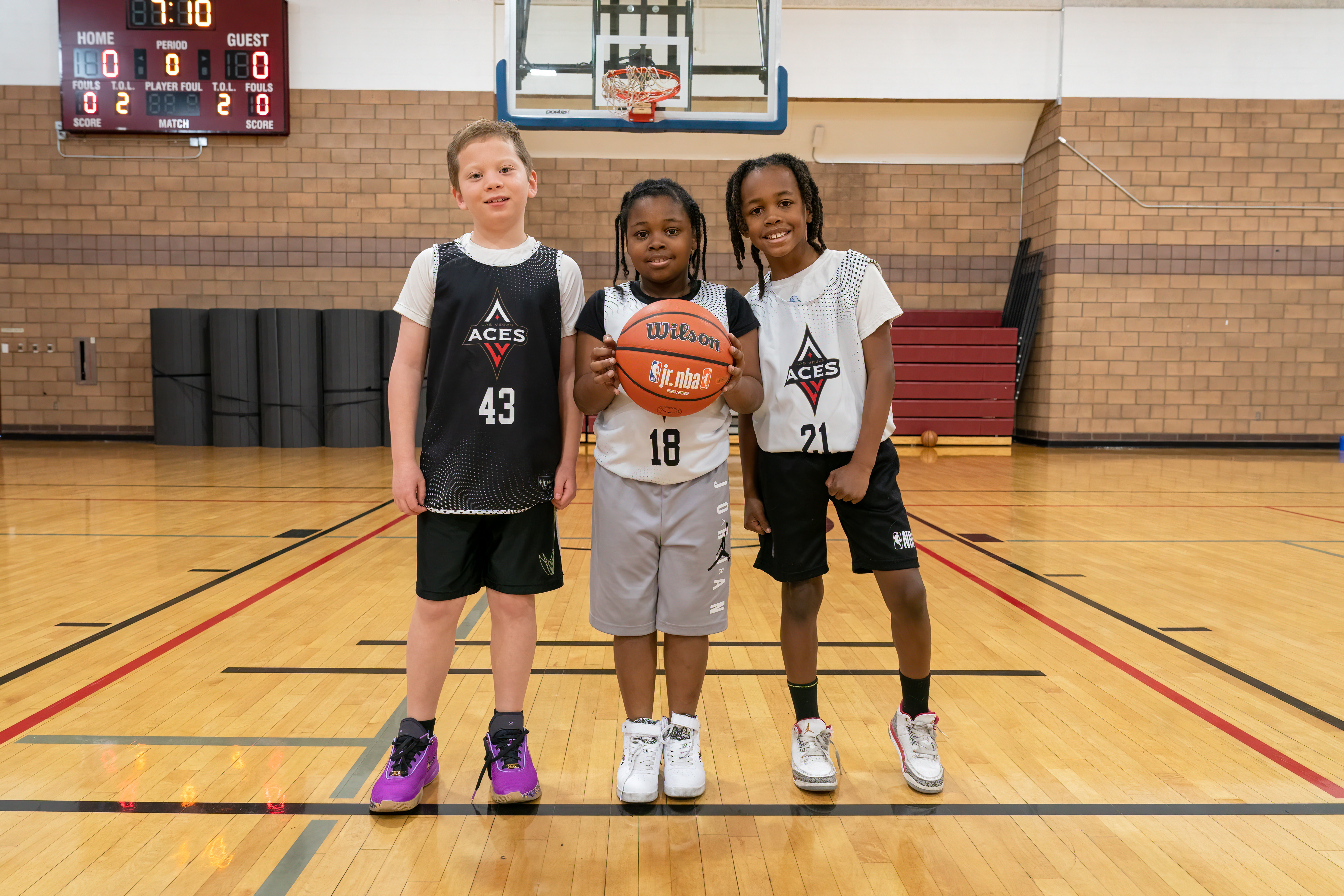 Three kids at a basketball court wearing Jr. NBA jerseys Three kids at a basketball court wearing Jr. NBA jerseys