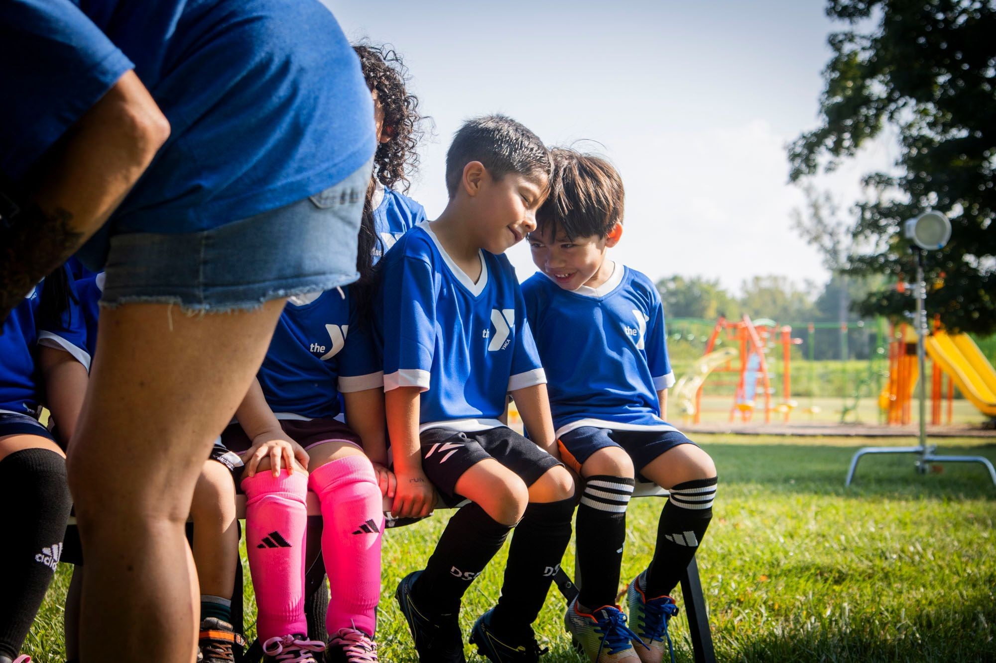 Two boys in YMCA soccer uniforms sitting on bench Two boys in YMCA soccer uniforms sitting on bench