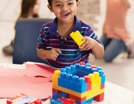Kid building with colorful blocks at YMCA child care program Kid building with colorful blocks at YMCA child care program