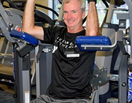 Man smiling while working out on machine wearing a Livestrong shirt Man smiling while working out on machine wearing a Livestrong shirt
