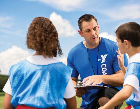 Coach talking to kids for YMCA Louisville youth fitness program Coach talking to kids for YMCA Louisville youth fitness program