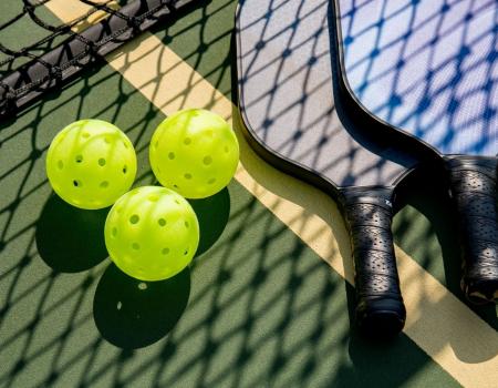 Pickleballs and paddles on the ground on a pickleball court Pickleballs and paddles on the ground on a pickleball court