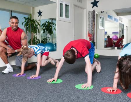 Group of kids working with a trainer training for YMCA youth sports Group of kids working with a trainer training for YMCA youth sports