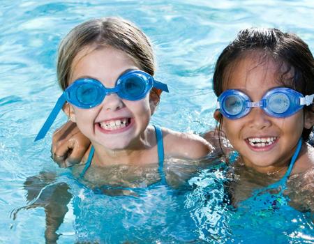 Two smiling kids in swim goggles in the pool at the YMCA Two smiling kids in swim goggles in the pool at the YMCA