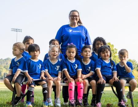 Woman and children wearing soccer uniforms standing and smiling as they are getting their picture taken Woman and children wearing soccer uniforms standing and smiling as they are getting their picture taken